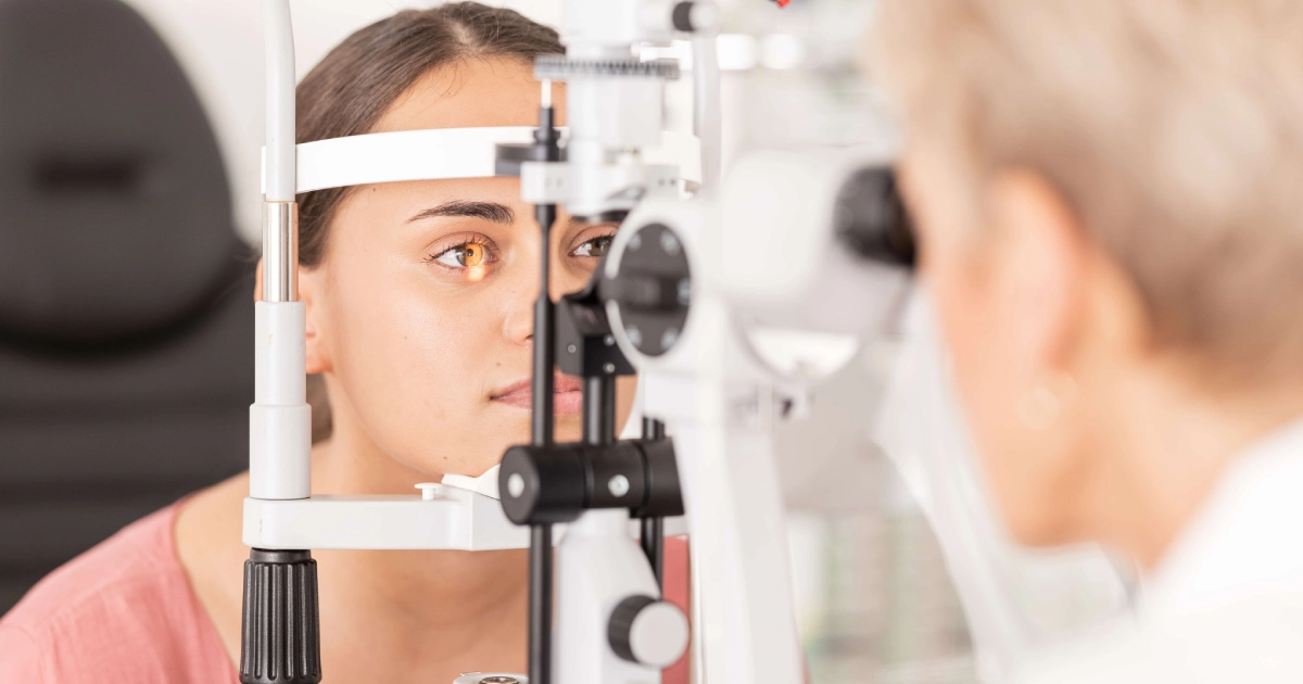 Close-up of a young woman undergoing a Comprehensive Eye Exams treatment in Chicago, IL, with her chin on the stand while an optometrist examines her eye.